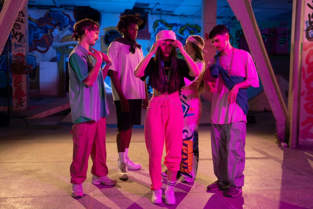 A vibrant group of young adults dancing in a neon graffiti-covered urban environment.